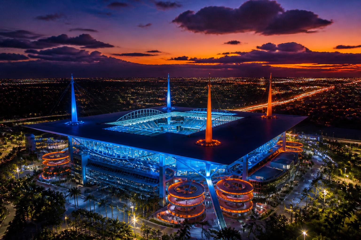 Hard Rock Stadium de Miami iluminado de noche con palmeras y vibe tropical