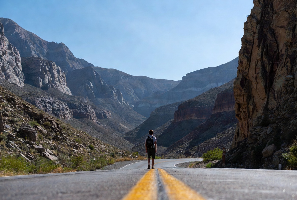 Viajero caminando solo por una carretera entre cañones del suroeste americano
